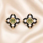 Green crystal pearl cross earring making kit E012 flat lay showing green rhinestone, white crystal pearls, and black and gold Miyuki seed beads on a neutral background