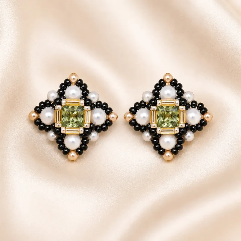 Green crystal pearl cross earring making kit E012 flat lay showing green rhinestone, white crystal pearls, and black and gold Miyuki seed beads on a neutral background